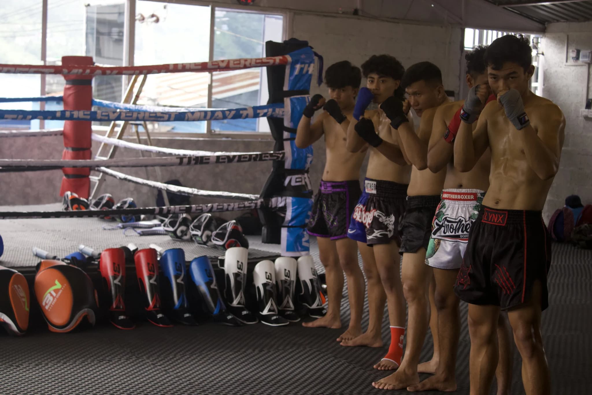 The ring at The Everest Muay Thai with fighters and training gear alongside